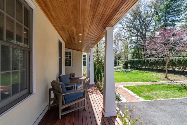 wooden terrace featuring a lawn and covered porch