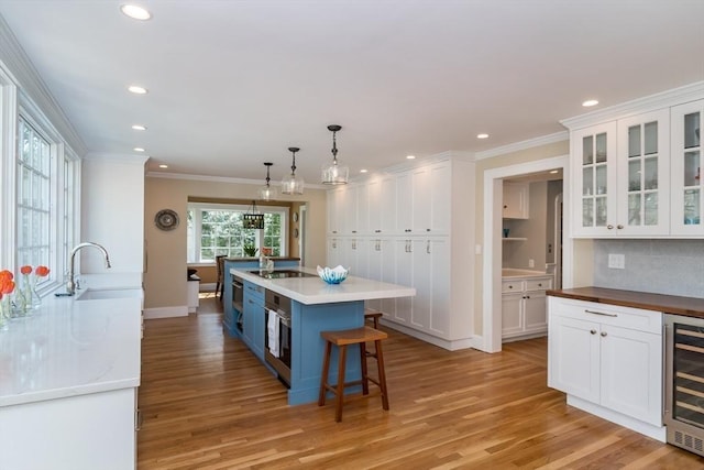 kitchen with beverage cooler, white cabinetry, recessed lighting, and ornamental molding