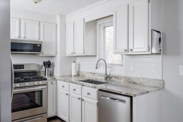 kitchen with sink, crown molding, stainless steel appliances, light stone countertops, and white cabinets