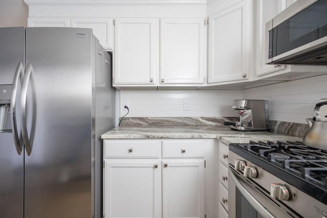 kitchen featuring stainless steel appliances, light stone countertops, and white cabinets