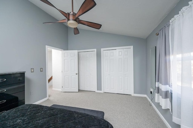 carpeted bedroom with lofted ceiling, two closets, and ceiling fan