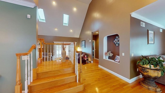 stairway featuring wood finished floors, arched walkways, baseboards, high vaulted ceiling, and crown molding