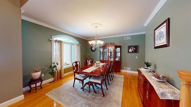 dining room featuring a chandelier, crown molding, light wood-style flooring, and baseboards