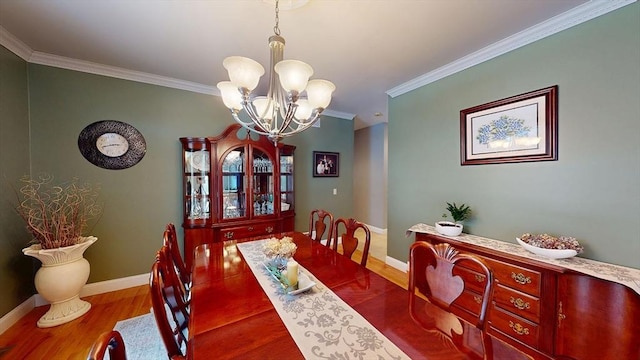 dining space with wood finished floors, crown molding, a chandelier, and baseboards
