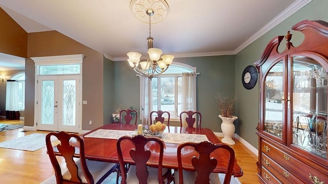 dining room with a chandelier, light wood-type flooring, french doors, ornamental molding, and baseboards