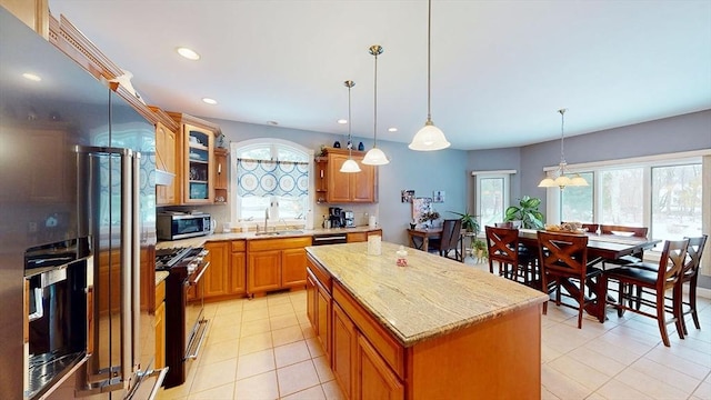 kitchen with stainless steel appliances, a center island, light tile patterned flooring, pendant lighting, and glass insert cabinets
