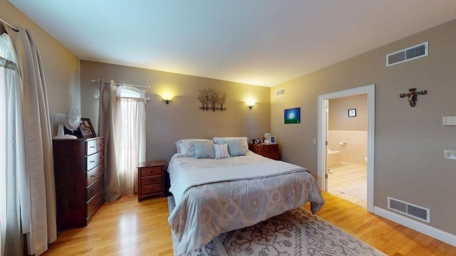 bedroom featuring light wood finished floors and ensuite bathroom