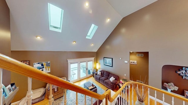 living room featuring high vaulted ceiling, a skylight, wood finished floors, recessed lighting, and stairway