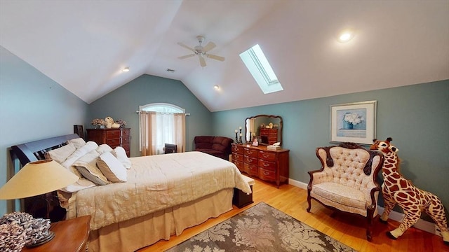 bedroom featuring a skylight, light wood-style floors, lofted ceiling, a ceiling fan, and baseboards
