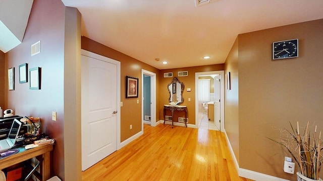 corridor featuring light wood-style flooring, baseboards, and recessed lighting