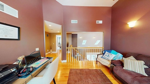 living area with a towering ceiling, wood finished floors, and baseboards