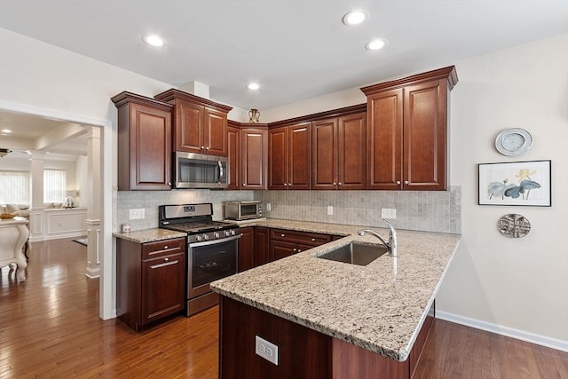 123 Skyline Dr Unit 123, Acton, MA 01720 - kitchen featuring stainless steel appliances, ornate columns, a sink, a peninsula, and dark wood-style floors