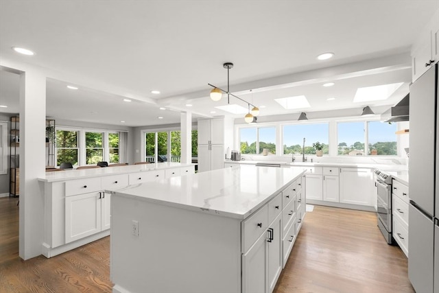 21 Glenley Ter, Boston, MA 02135 - kitchen featuring a skylight, light wood-type flooring, a kitchen island, stainless steel refrigerator, and white cabinetry