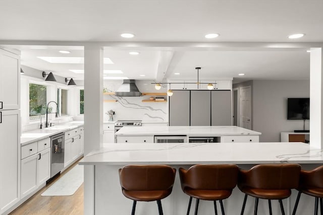 21 Glenley Ter, Boston, MA 02135 - kitchen with a kitchen island, stainless steel appliances, wall chimney exhaust hood, light stone countertops, and light wood-style flooring