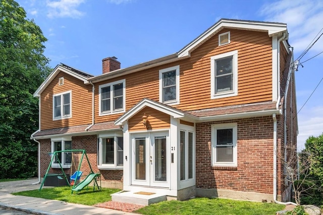 21 Glenley Ter, Boston, MA 02135 - view of front of home with french doors, a chimney, brick siding, and a front lawn