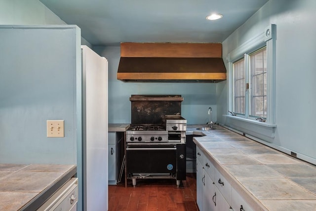 41 Bulkley, Williamstown, MA 01267 - kitchen with tile countertops, freestanding refrigerator, wall chimney exhaust hood, white cabinetry, and a sink