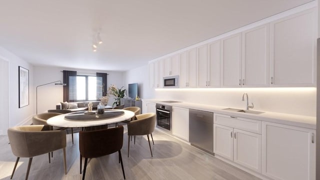 kitchen with sink, light hardwood / wood-style floors, white cabinets, and appliances with stainless steel finishes