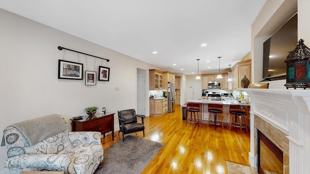 living room with light wood finished floors, a tiled fireplace, and recessed lighting