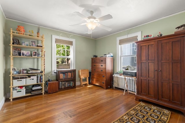 interior space featuring crown molding, a ceiling fan, radiator, and hardwood / wood-style floors