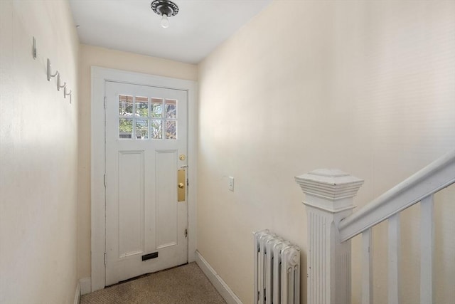 doorway to outside with baseboards, carpet floors, and radiator heating unit