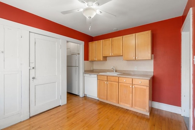 kitchen with a ceiling fan, a sink, light countertops, baseboards, and white appliances