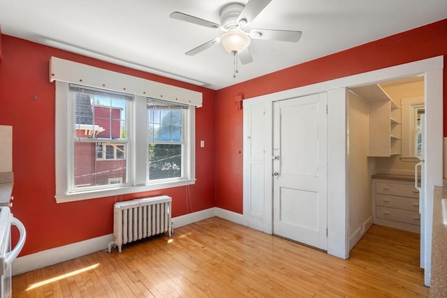 foyer with radiator heating unit, baseboards, ceiling fan, and light wood-type flooring
