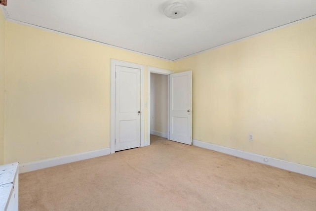 spare room featuring baseboards and light carpet
