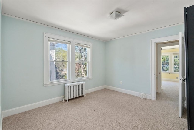 spare room with radiator heating unit, light carpet, and a healthy amount of sunlight