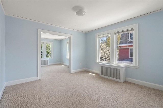carpeted spare room featuring baseboards and radiator heating unit