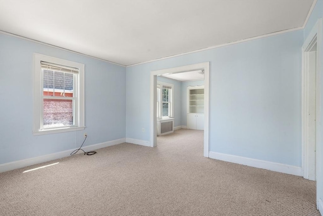 spare room with baseboards, crown molding, and light carpet
