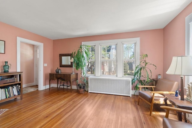 sitting room featuring light wood-style floors, radiator, and baseboards