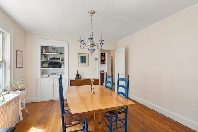 dining area with an inviting chandelier, baseboards, crown molding, and wood finished floors