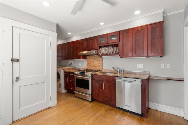 kitchen with crown molding, washer / clothes dryer, under cabinet range hood, a sink, and stainless steel appliances