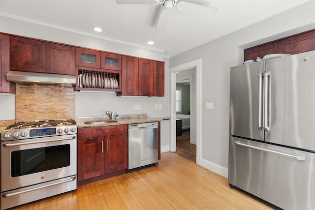 kitchen featuring backsplash, a sink, under cabinet range hood, stainless steel appliances, and light wood-style flooring