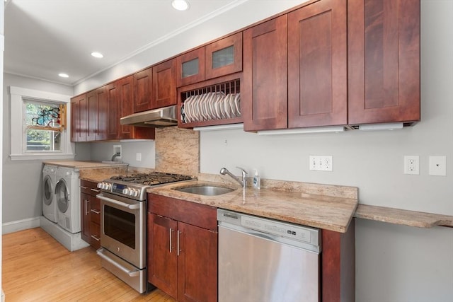kitchen featuring backsplash, independent washer and dryer, appliances with stainless steel finishes, a sink, and under cabinet range hood