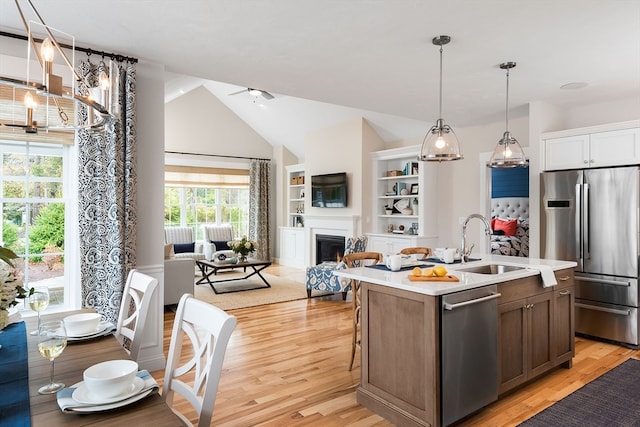 kitchen featuring hanging light fixtures, sink, an island with sink, lofted ceiling, and stainless steel appliances