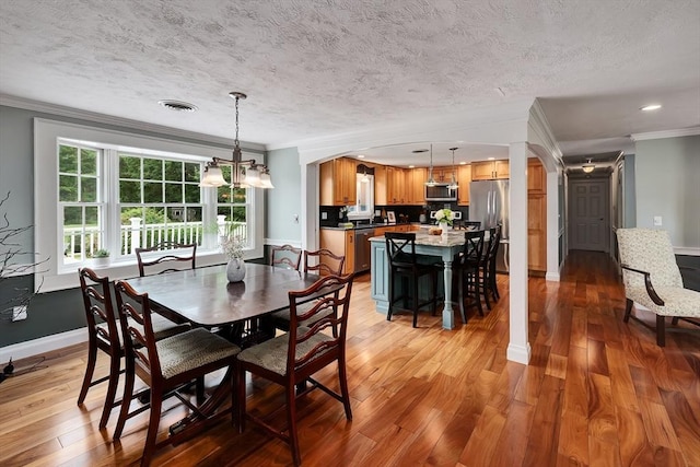 7 Perkins Row, Topsfield, MA 01983 - dining room with crown molding, light wood-type flooring, a chandelier, arched walkways, and a textured ceiling