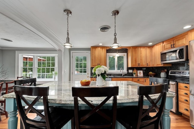 7 Perkins Row, Topsfield, MA 01983 - kitchen with stainless steel appliances, ornamental molding, decorative backsplash, a breakfast bar, and hanging light fixtures