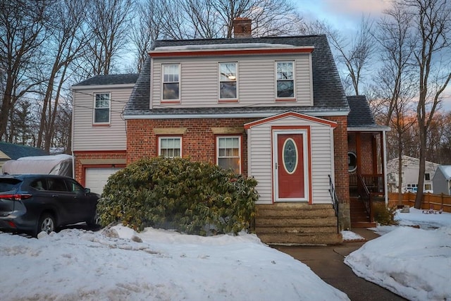 view of front of property featuring a garage, brick siding, a chimney, and a shingled roof