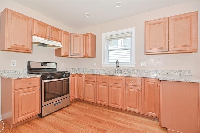 kitchen with sink, light hardwood / wood-style flooring, stainless steel gas stove, light stone countertops, and light brown cabinets