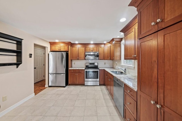 kitchen featuring stainless steel appliances, a sink, backsplash, brown cabinets, and light stone countertops