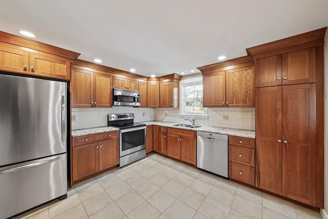 kitchen with appliances with stainless steel finishes, brown cabinetry, a sink, and decorative backsplash