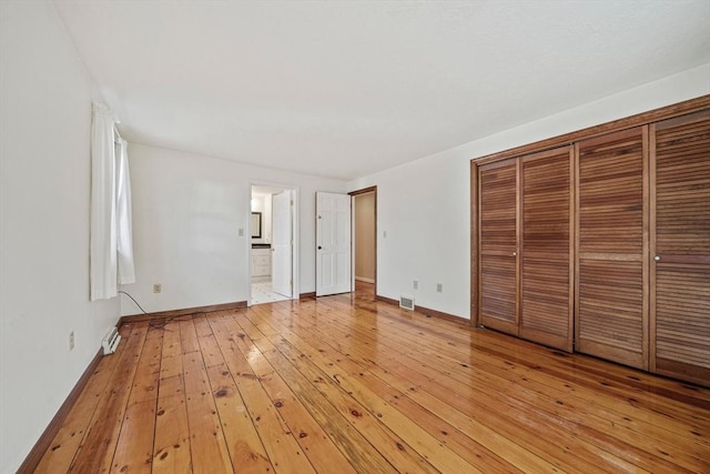 unfurnished bedroom with a closet, visible vents, light wood-style flooring, connected bathroom, and baseboards