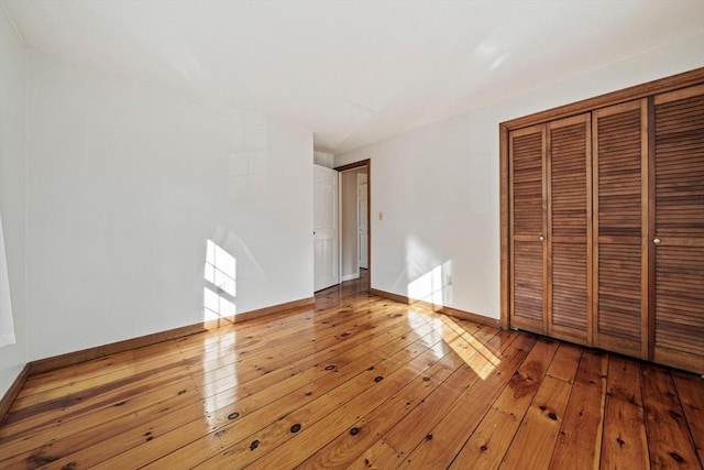 unfurnished bedroom with a closet, baseboards, and hardwood / wood-style flooring