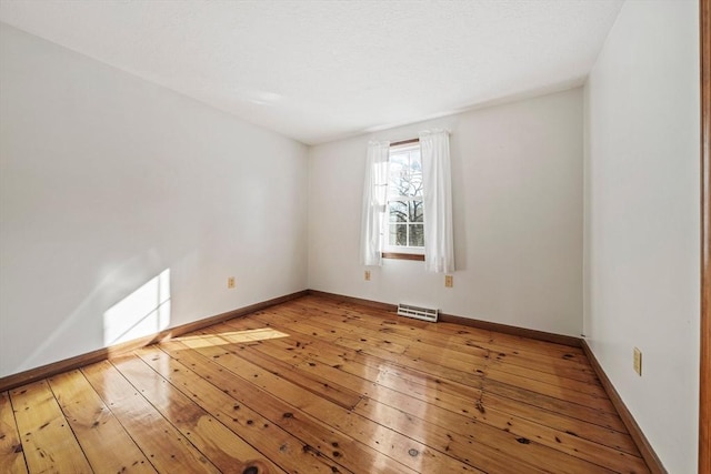 spare room with hardwood / wood-style floors, visible vents, and baseboards