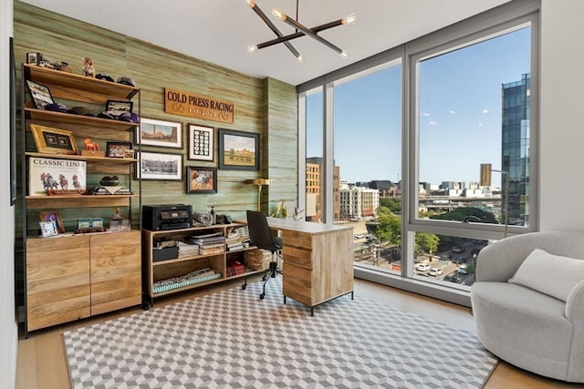 office space featuring wood-type flooring, expansive windows, an inviting chandelier, and wooden walls