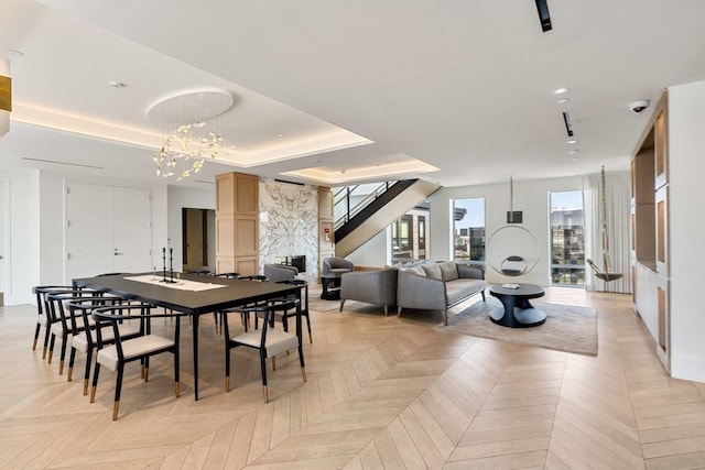 dining room with a tray ceiling, light parquet floors, a premium fireplace, and a chandelier