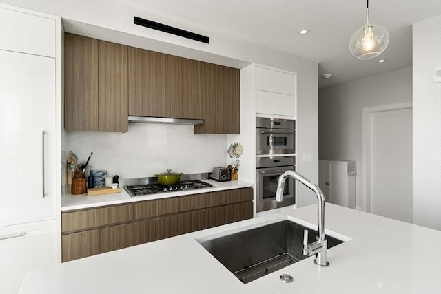 kitchen with range hood, stainless steel appliances, white cabinetry, sink, and pendant lighting