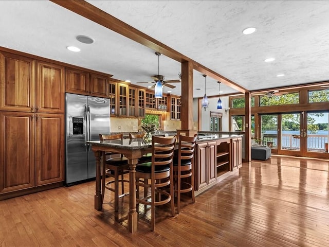 91 Lake Shore Dr, West Brookfield, MA 01585 - kitchen featuring stainless steel refrigerator with ice dispenser, glass insert cabinets, wood-type flooring, french doors, and a kitchen breakfast bar