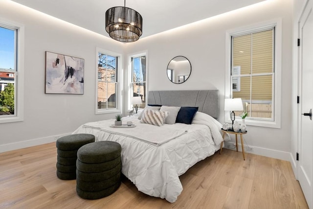 bedroom with an inviting chandelier and light hardwood / wood-style flooring